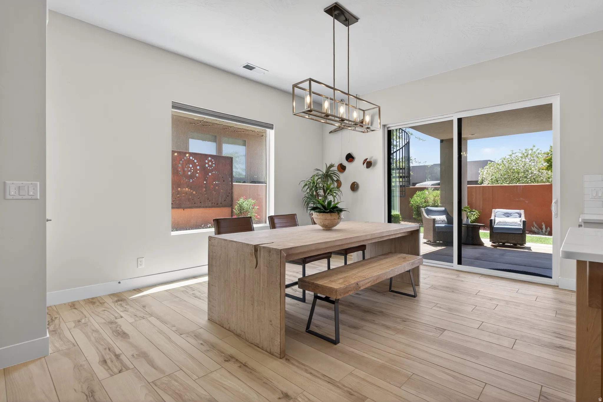 Dining area featuring wood-finish tile flooring, a large window, and sliding glass doors opening to a private patio