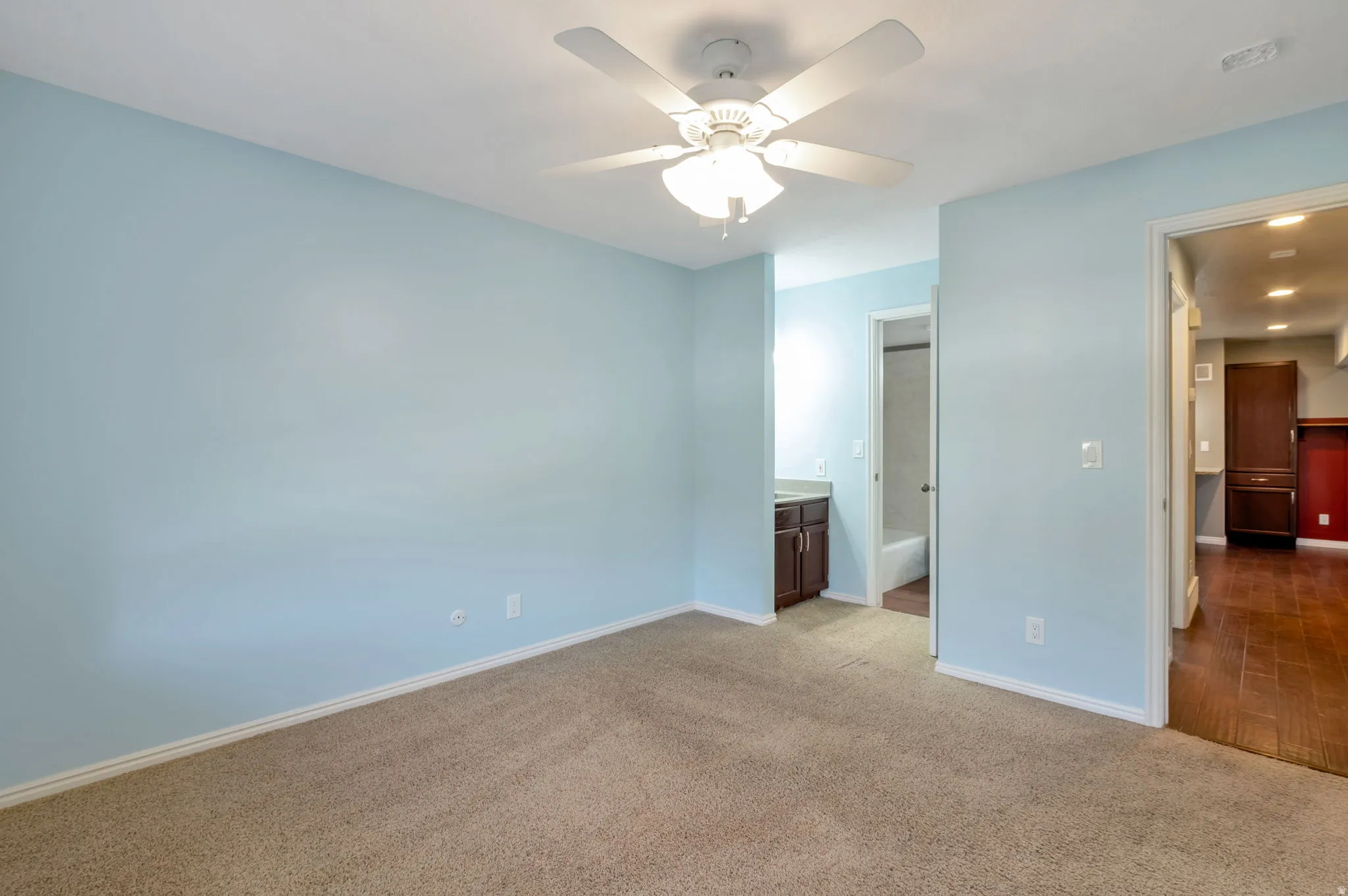 Carpeted room with a ceiling fan, light blue walls, and white trim