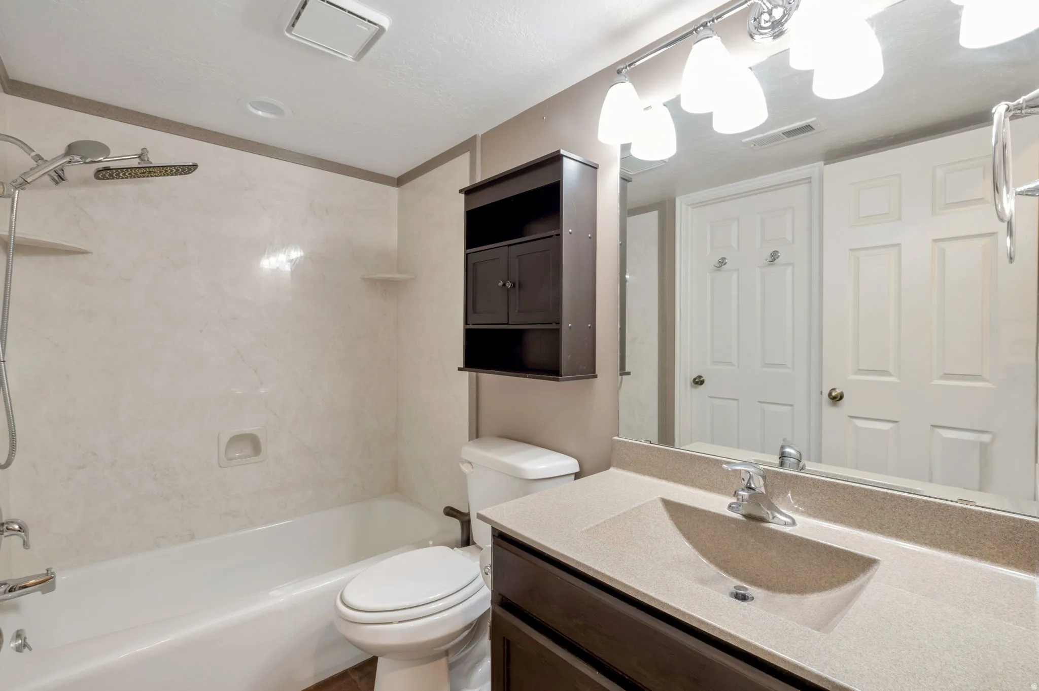 Bathroom featuring a tub/shower combination with a rain shower head, a wall-mounted medicine cabinet, and a vanity with an integrated sink and countertop