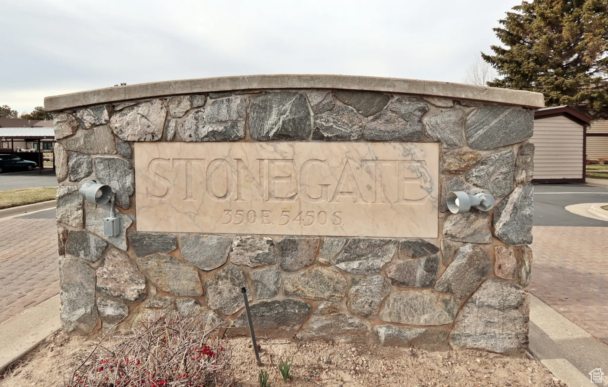 Stone facade monument sign featuring an engraved nameplate and integrated lighting fixtures