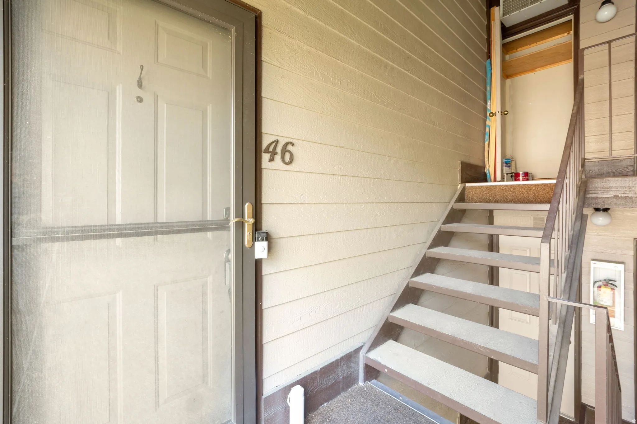 Entryway featuring beige horizontal siding and a dark brown screen door with a gold-tone handle