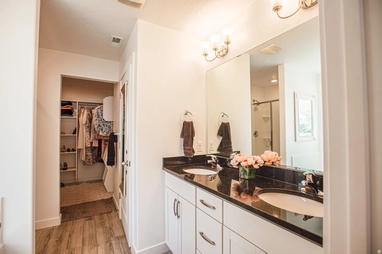 Bathroom vanity featuring a dual sink, dark countertop, and white cabinetry