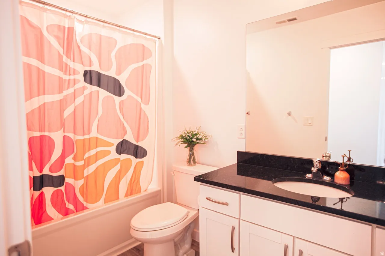 Bathroom vanity with a dark countertop and integrated sink, framed by a large wall-mounted mirror