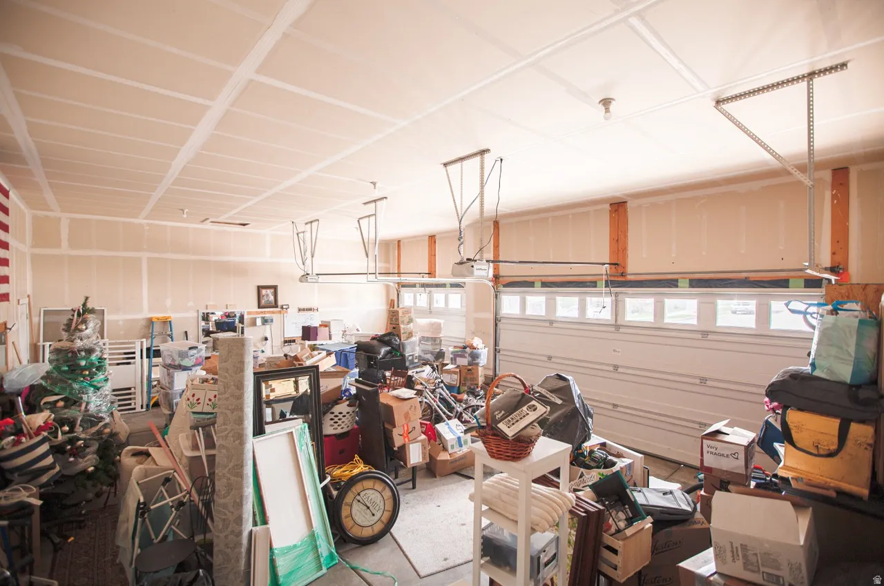 Spacious garage featuring drywall-finished walls and ceiling, two garage doors with upper window panels, and exposed wood framing