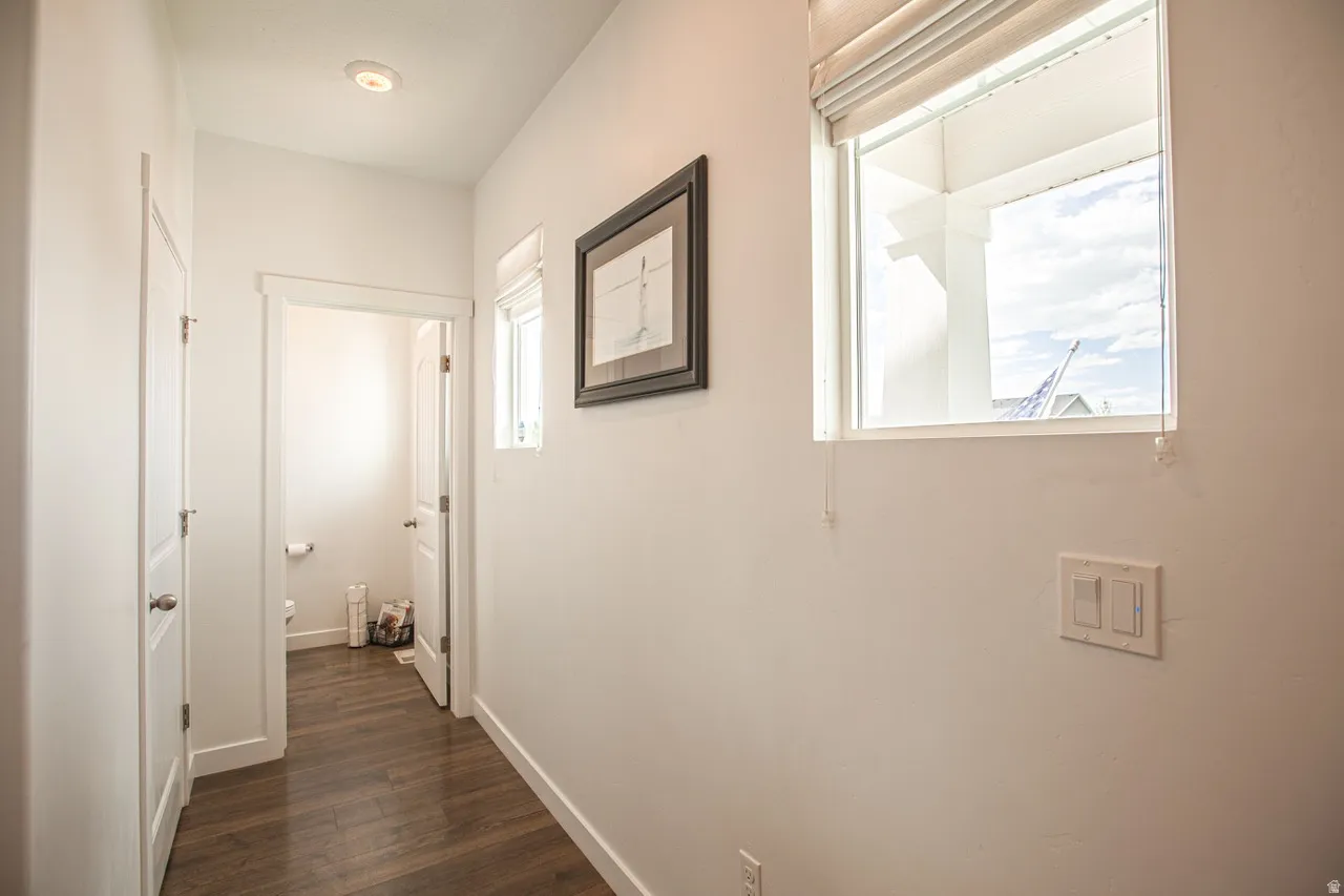 Hallway featuring wood-finish flooring, recessed lighting, and a window with a Roman shade