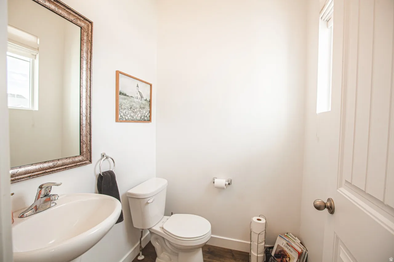 Compact bathroom featuring a wall-mounted sink with chrome fixtures, a framed mirror, and a white toilet
