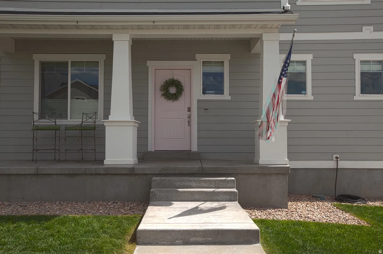 Front exterior featuring horizontal siding, a light pink entry door, white trim, and a concrete porch with steps