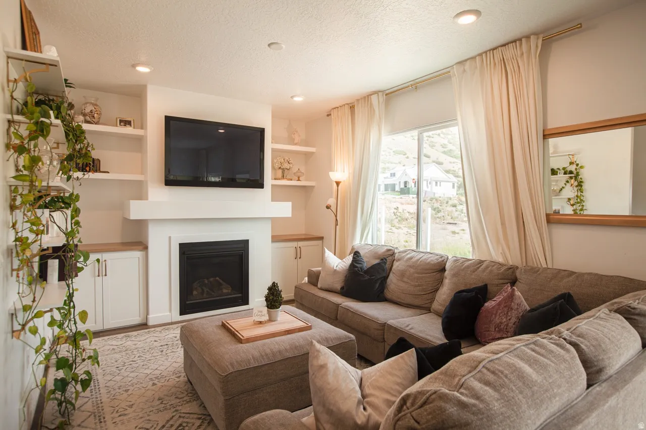 Living area featuring a built-in fireplace with a mantel, integrated shelving, and lower cabinetry with wood-finish countertops