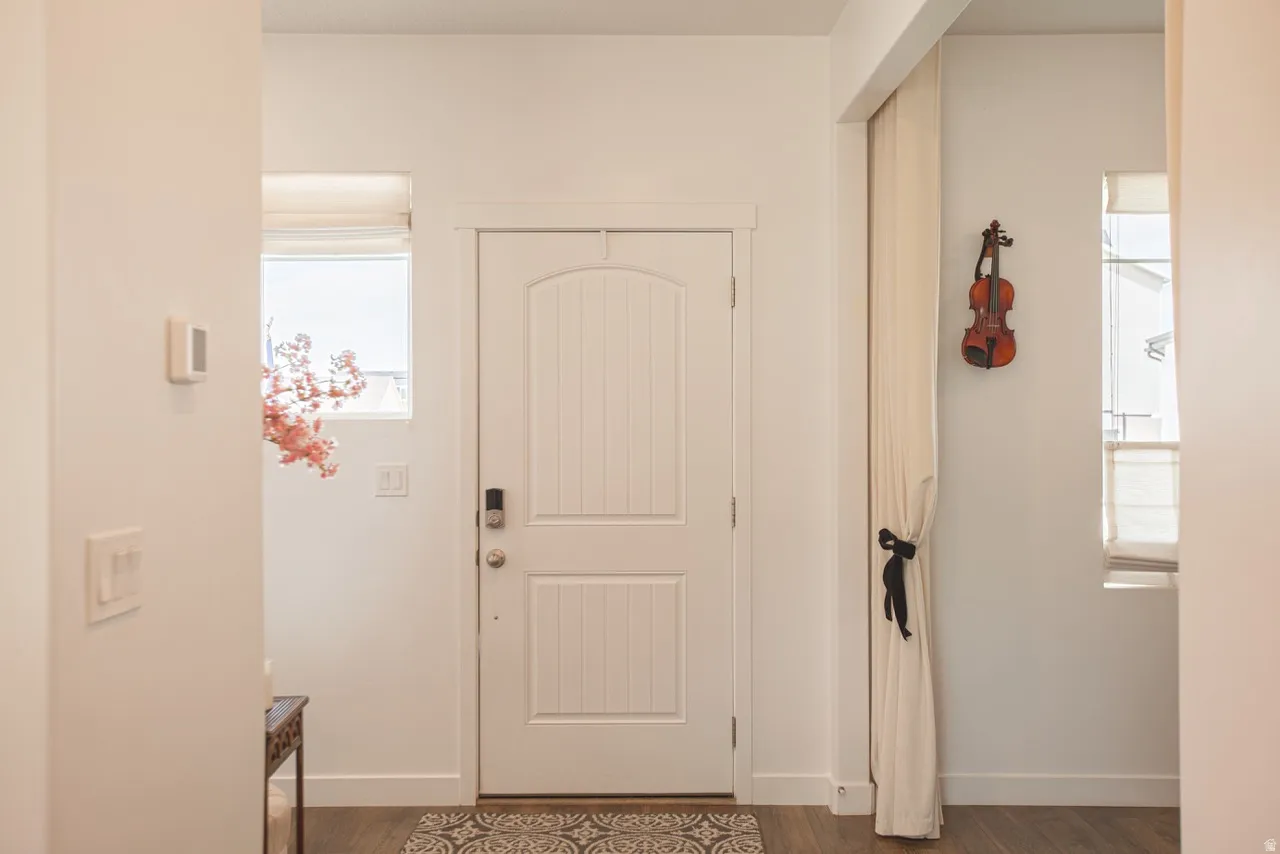 Entryway featuring a white paneled door with a smart lock, wood-finish flooring, and a transom window
