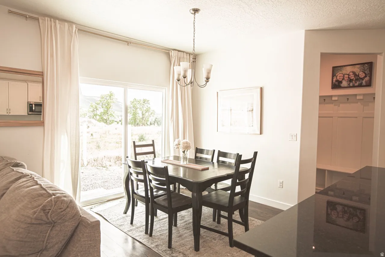 Dining area featuring sliding glass doors, a multi-light chandelier, and dark wood-finish flooring