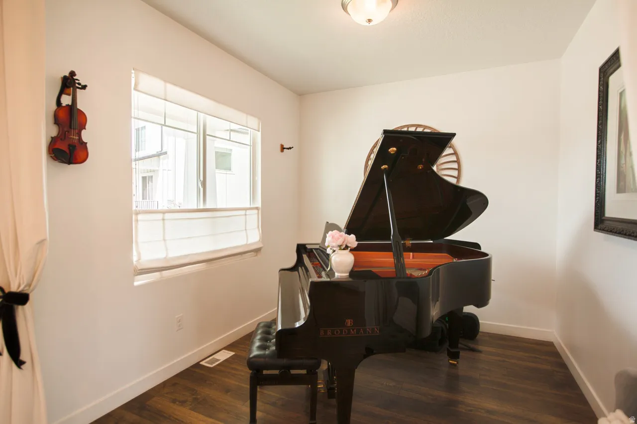 Bright interior space featuring wood-finish flooring, white walls, and a recessed window with blinds