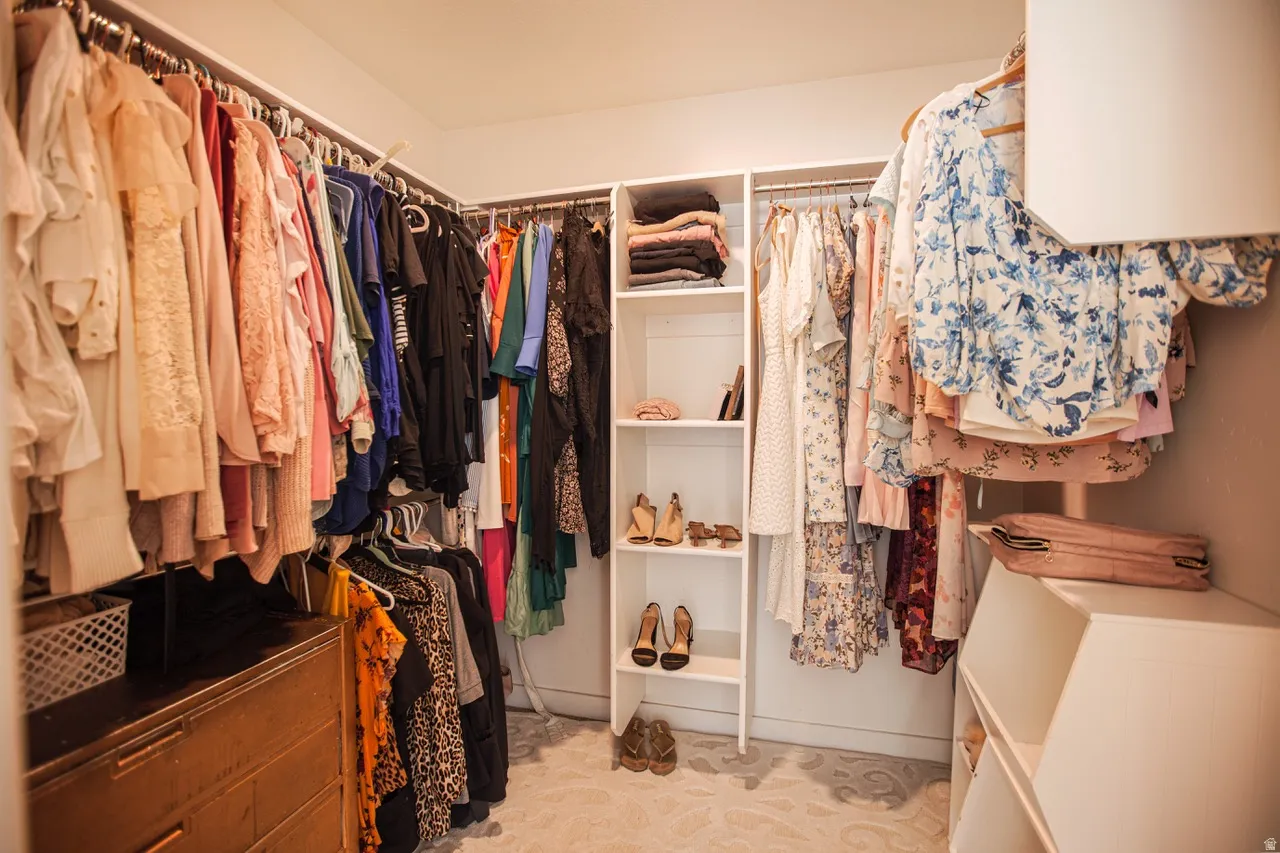 Walk-in closet featuring built-in shelving, multiple hanging rods, and a patterned area rug
