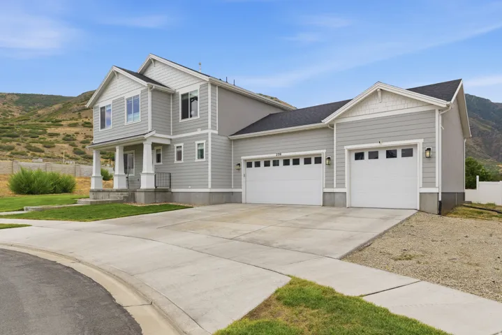 Two-story residence featuring light gray siding, white trim, and a dark roof