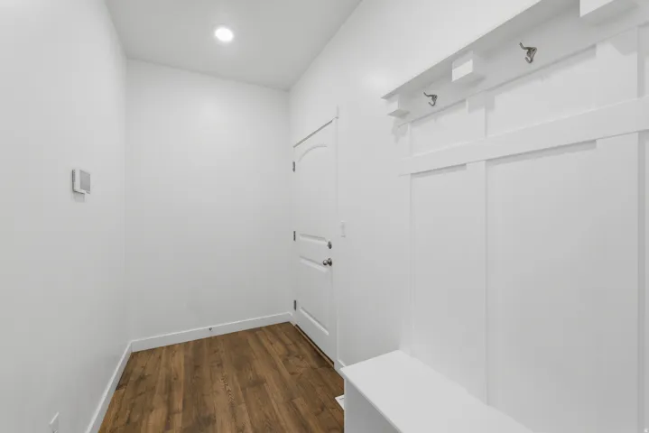 Wood-finish flooring, recessed lighting, and a built-in bench with coat hooks