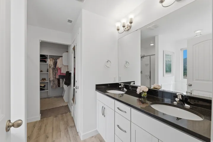 Dual vanity with dark stone countertops, undermount sinks, and chrome fixtures