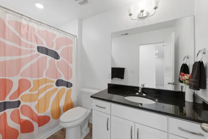 Bathroom with white vanity, dark countertop, and integrated sink