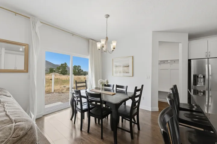 Spacious dining area featuring wood-finish flooring, a contemporary chandelier, and large sliding glass doors
