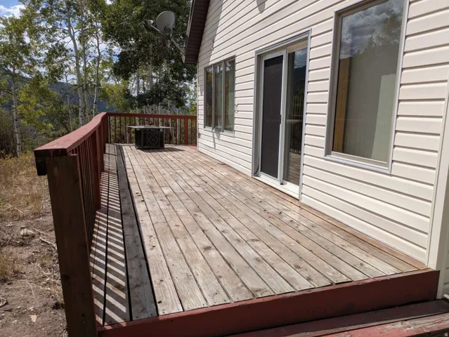 Expansive wood deck with a red painted railing, offering direct access to the interior via a sliding glass door