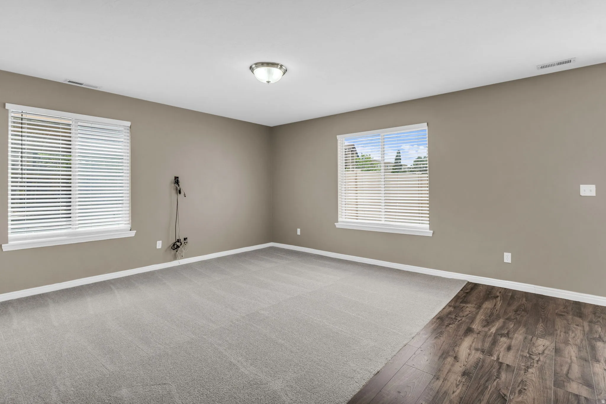 Spacious room featuring neutral tone walls and a ceiling-mounted light fixture.