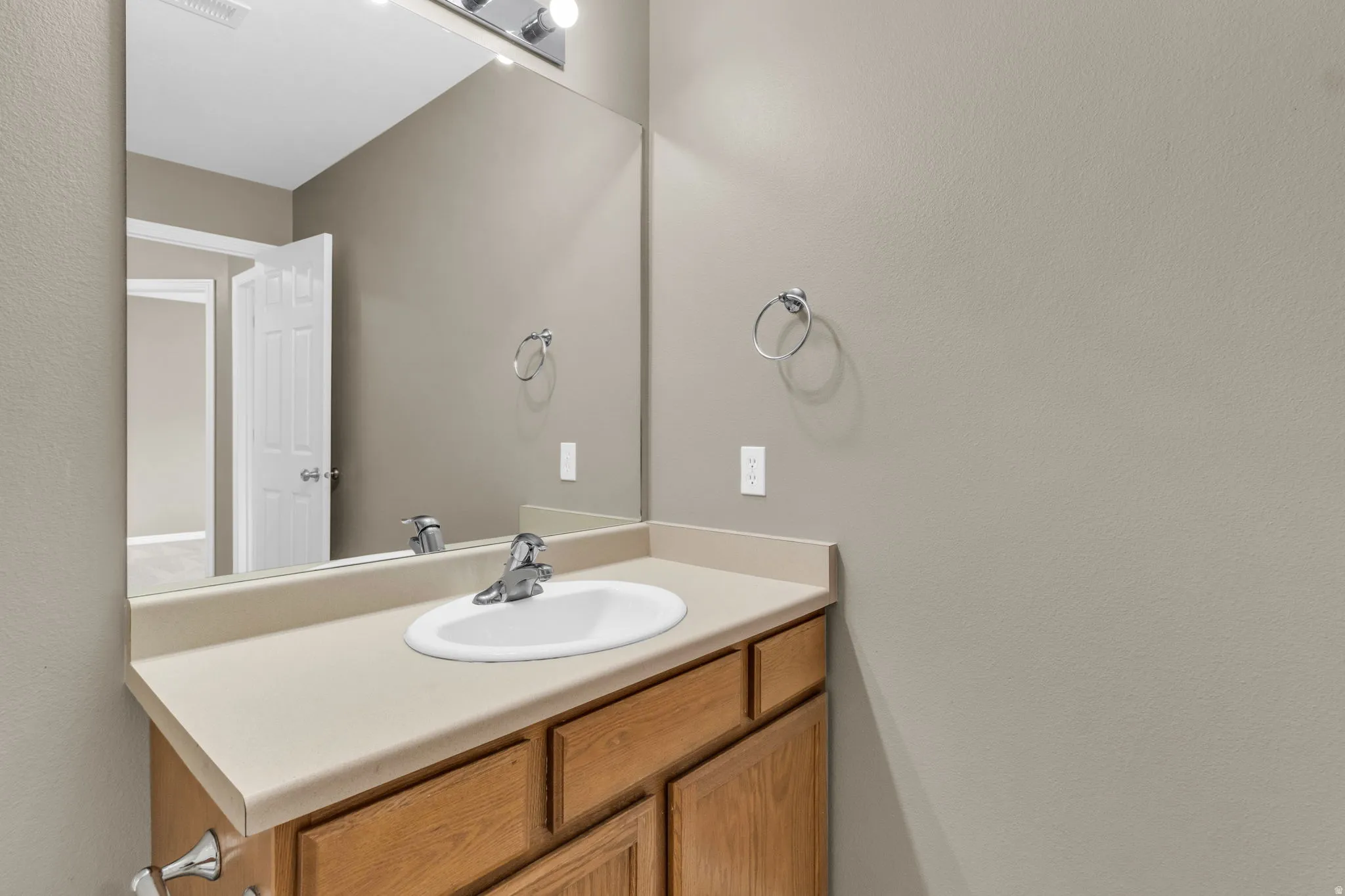 Bathroom vanity featuring wood-finish cabinetry and a neutral-toned countertop with an integrated sink.