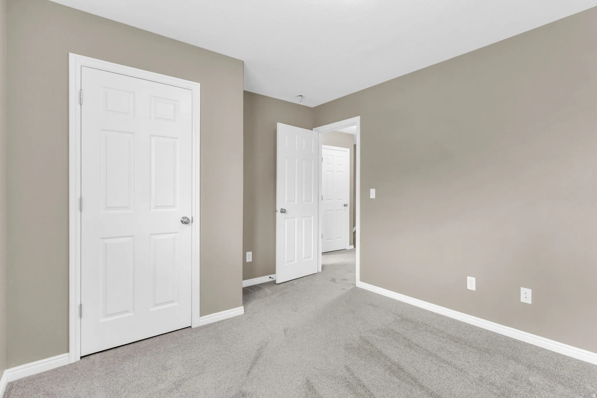 Neutral-toned room with plush grey carpeting and white baseboards.
