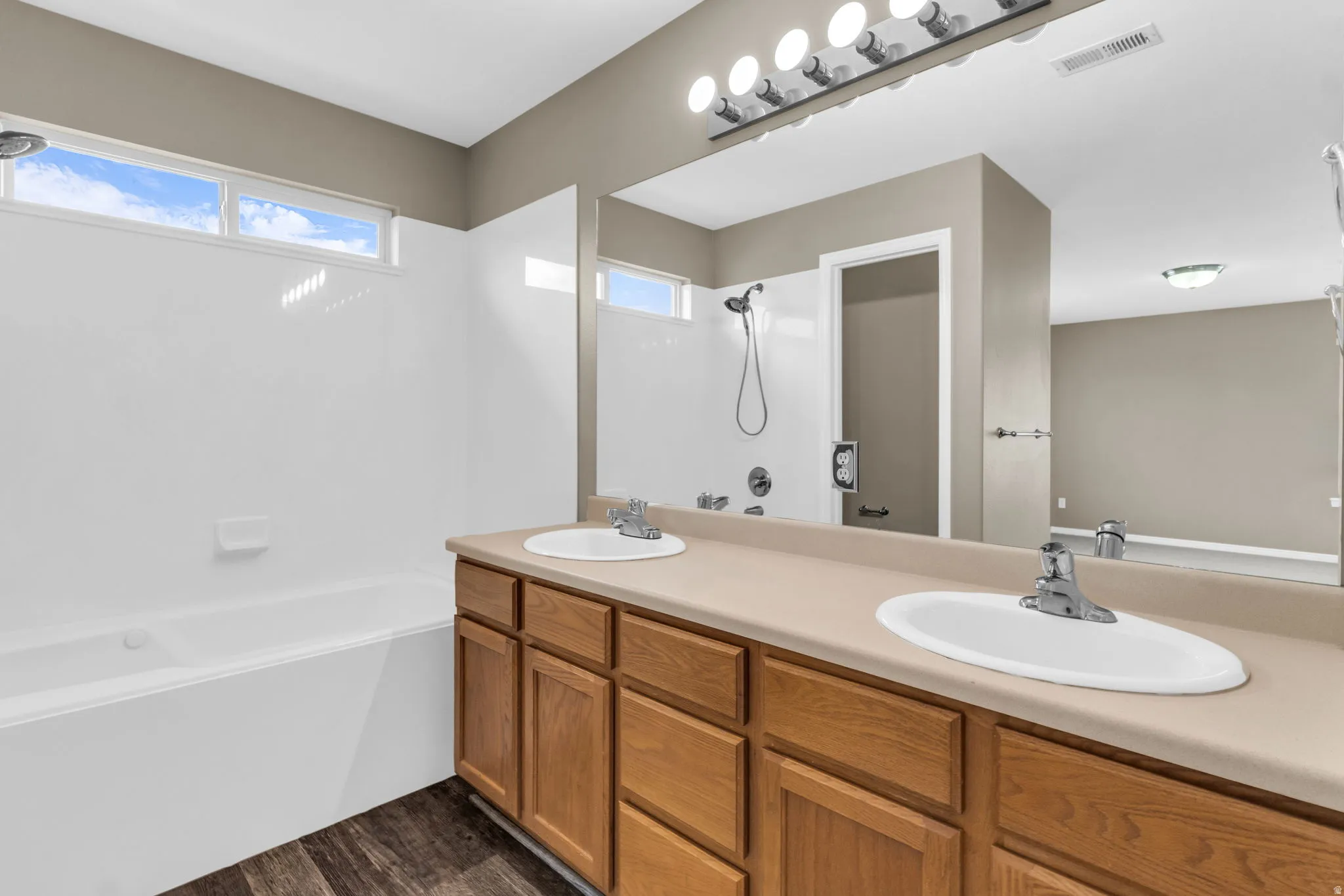 Primary Bathroom featuring a dual vanity with light wood cabinetry, white oval sinks, and chrome faucets.