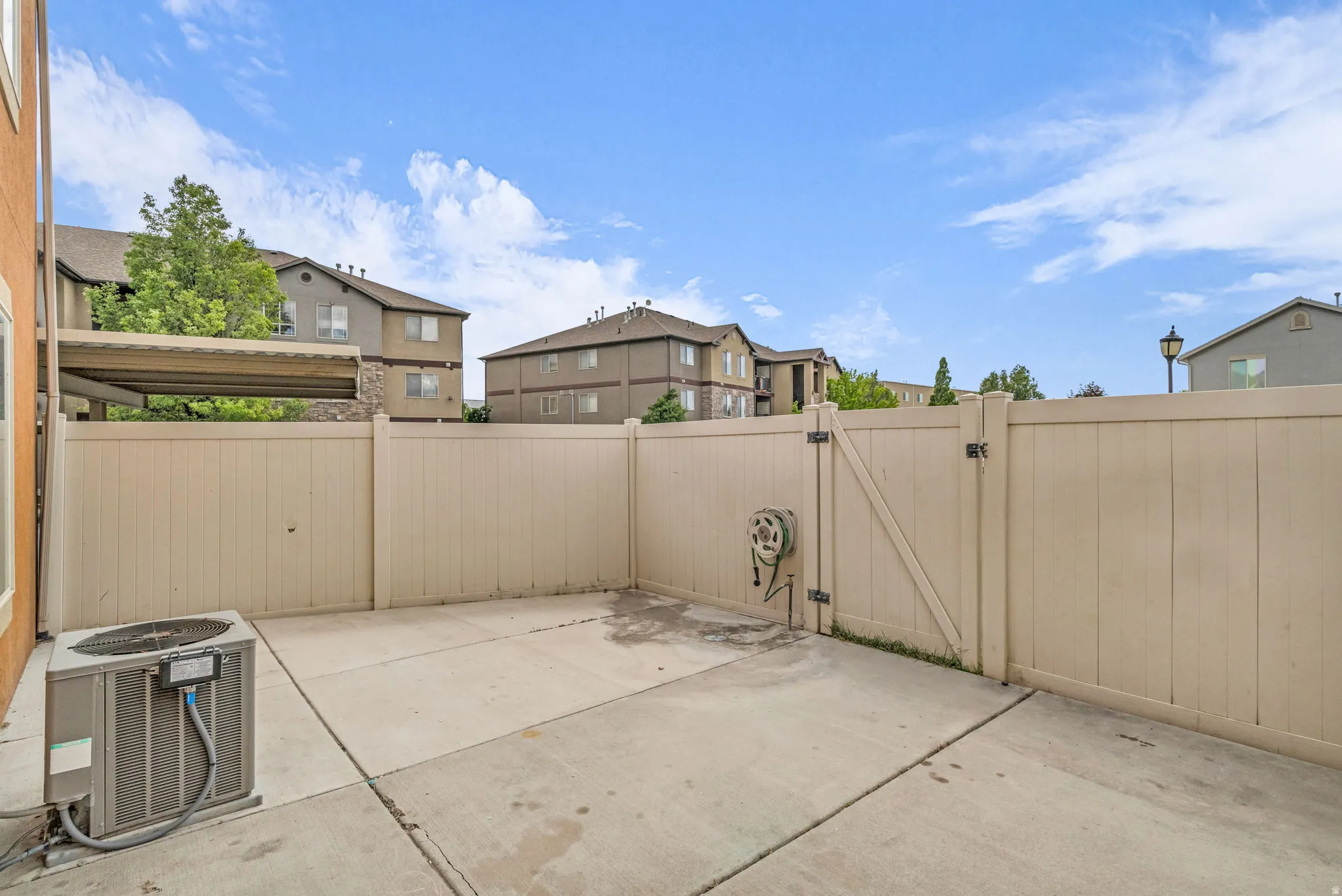 Private patio area featuring concrete flooring and a light-toned privacy fence, creating a clean and low-maintenance outdoor space.