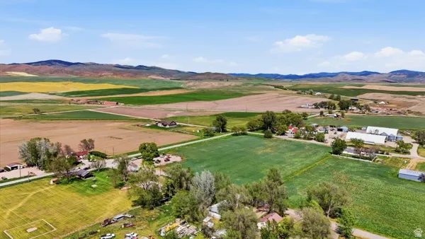 Expansive agricultural landscape featuring diverse fields, scattered residential structures, and distant mountains
