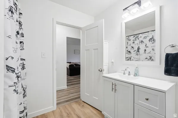 Vanity with integrated sink and chrome faucet, under-cabinet storage, and an overhead lighting fixture with a mirror
