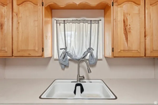 Kitchen featuring light wood cabinetry with decorative valance, dual basin sink, and a high-arc pull-down faucet