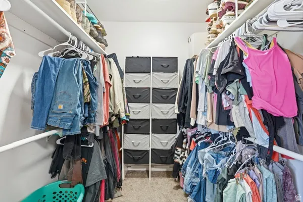 Walk-in closet featuring white wire shelving, hanging rods, and neutral-toned carpeting