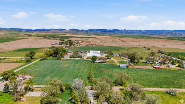 Expansive agricultural property featuring multiple fields, scattered outbuildings, and distant mountain ranges