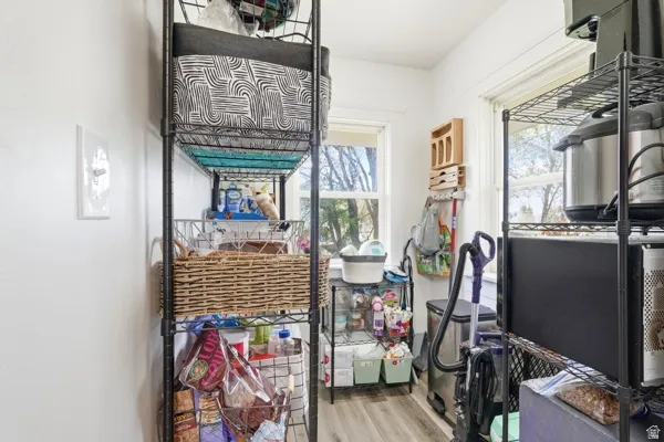 Utility room featuring light-toned wood-finish flooring, white walls, and two windows providing natural light