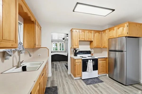 Kitchen featuring light wood cabinetry, white countertops, a double basin sink, and wood-finish flooring