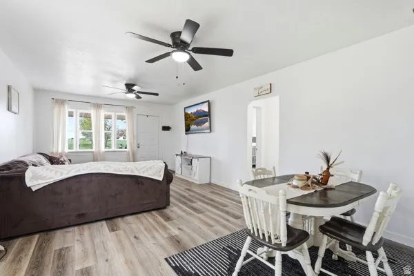 Open-concept living area featuring wood-finish flooring, white walls, and multiple ceiling fans