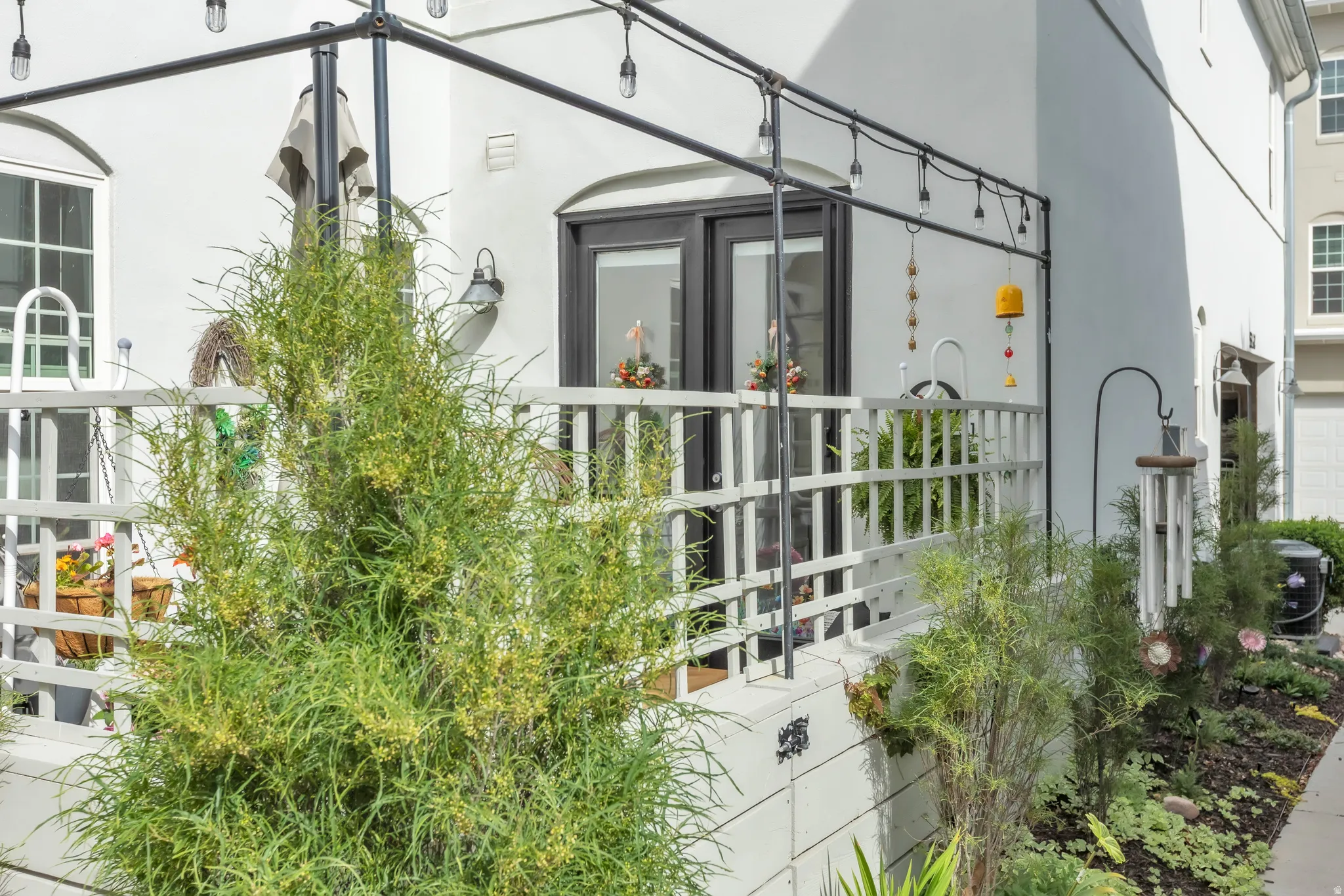Patio with white railing, featuring a dark-framed double door entry and an arched window