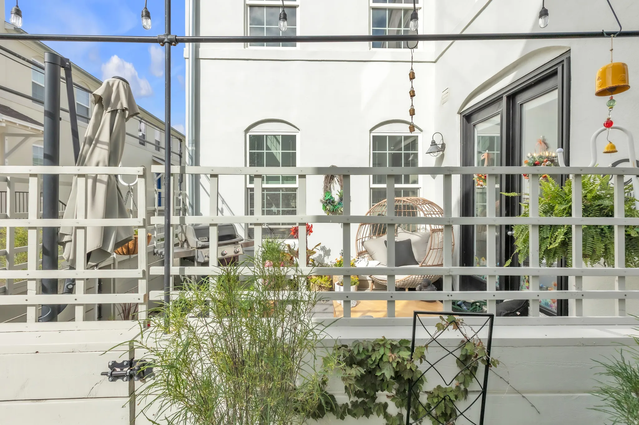 Upper-level patio with white lattice railing and string lighting