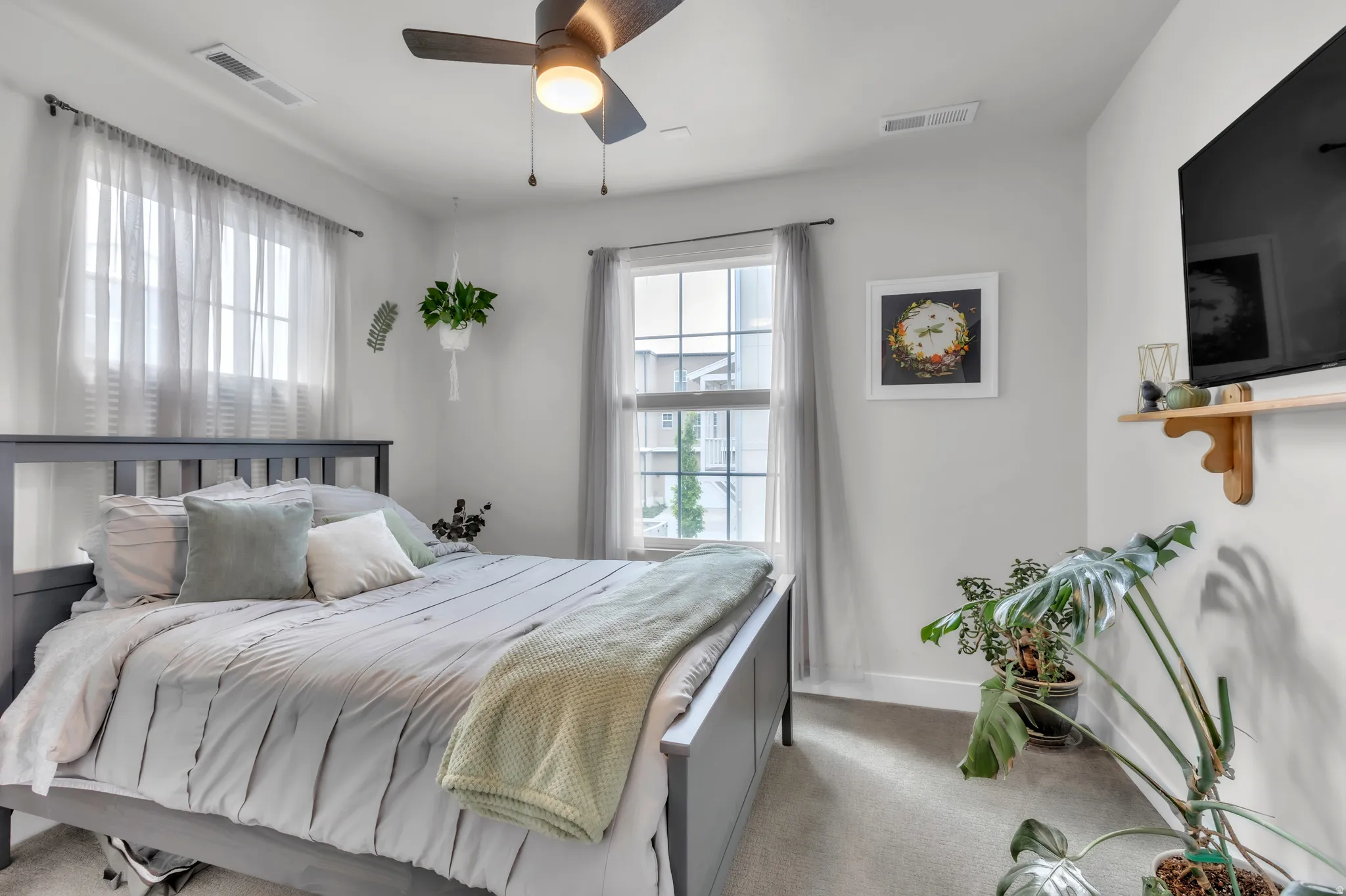 Bedroom featuring a contemporary ceiling fan with integrated lighting, neutral wall paint, and two windows providing natural light