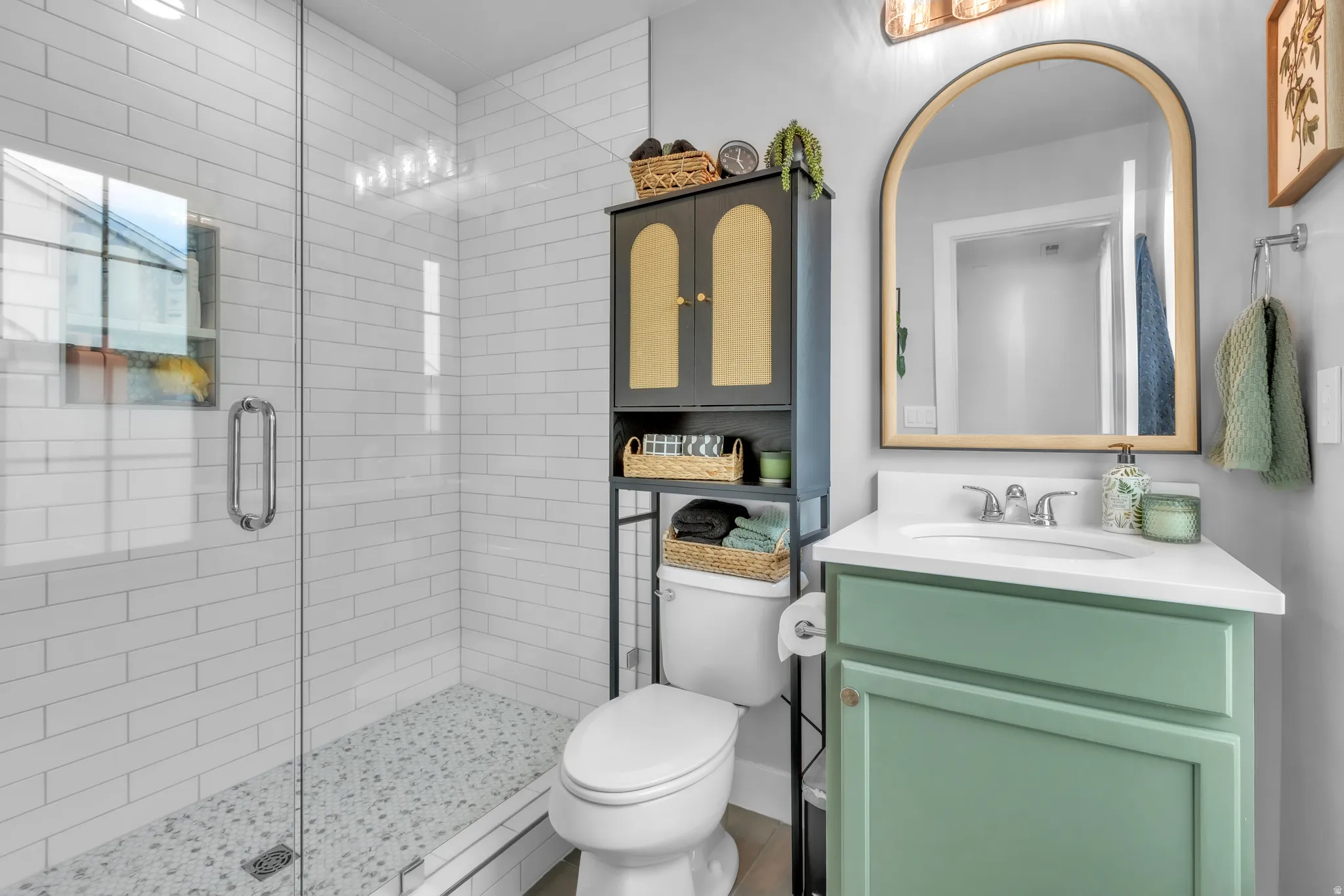 Glass-enclosed shower with white subway tile surround and pebble tile flooring