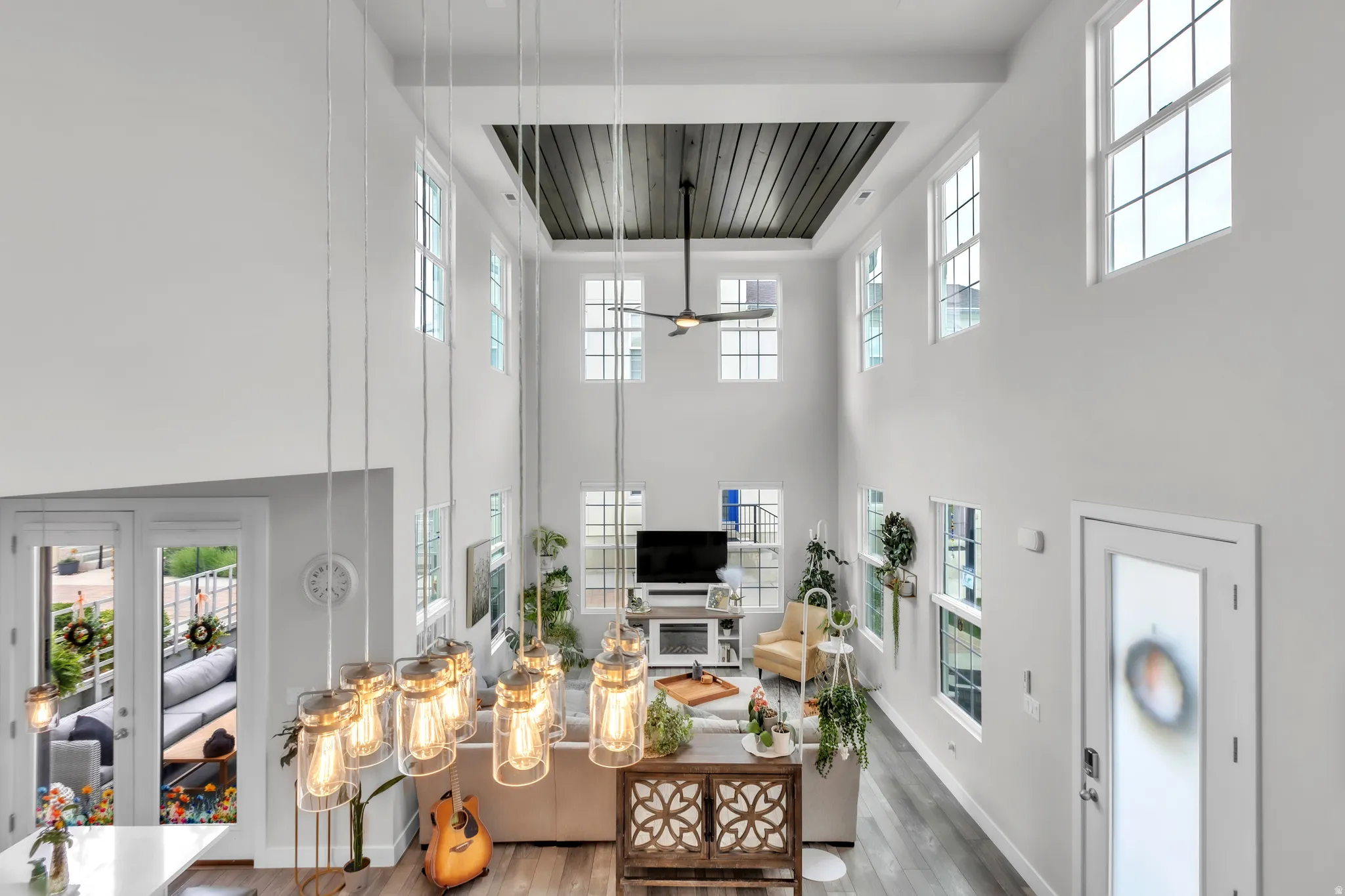 Two-story living area featuring a coffered ceiling with a ceiling fan, multiple transom windows, and wood-finish flooring