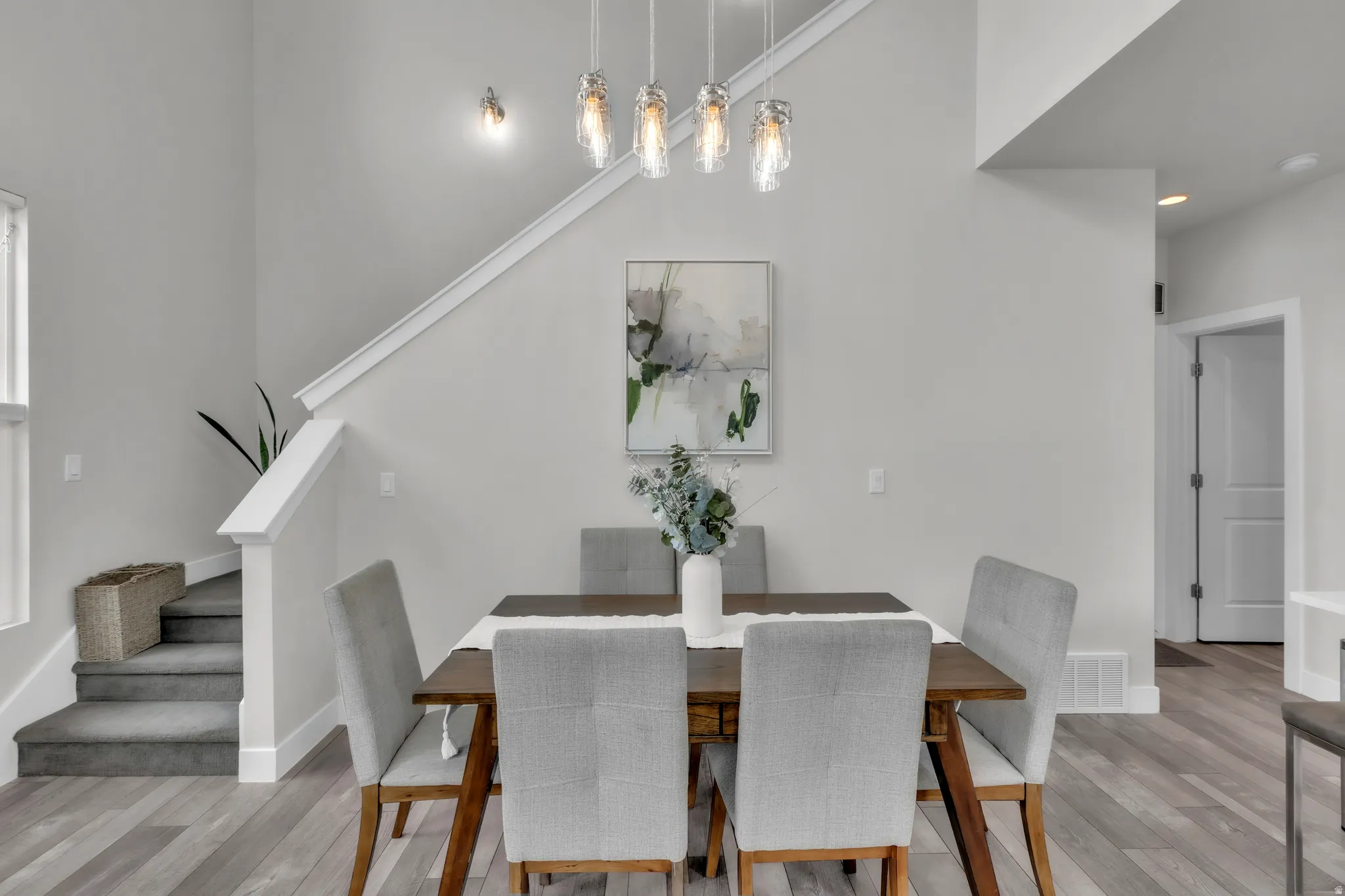 Dining area featuring wood-finish flooring, a contemporary chandelier, and a two-story ceiling
