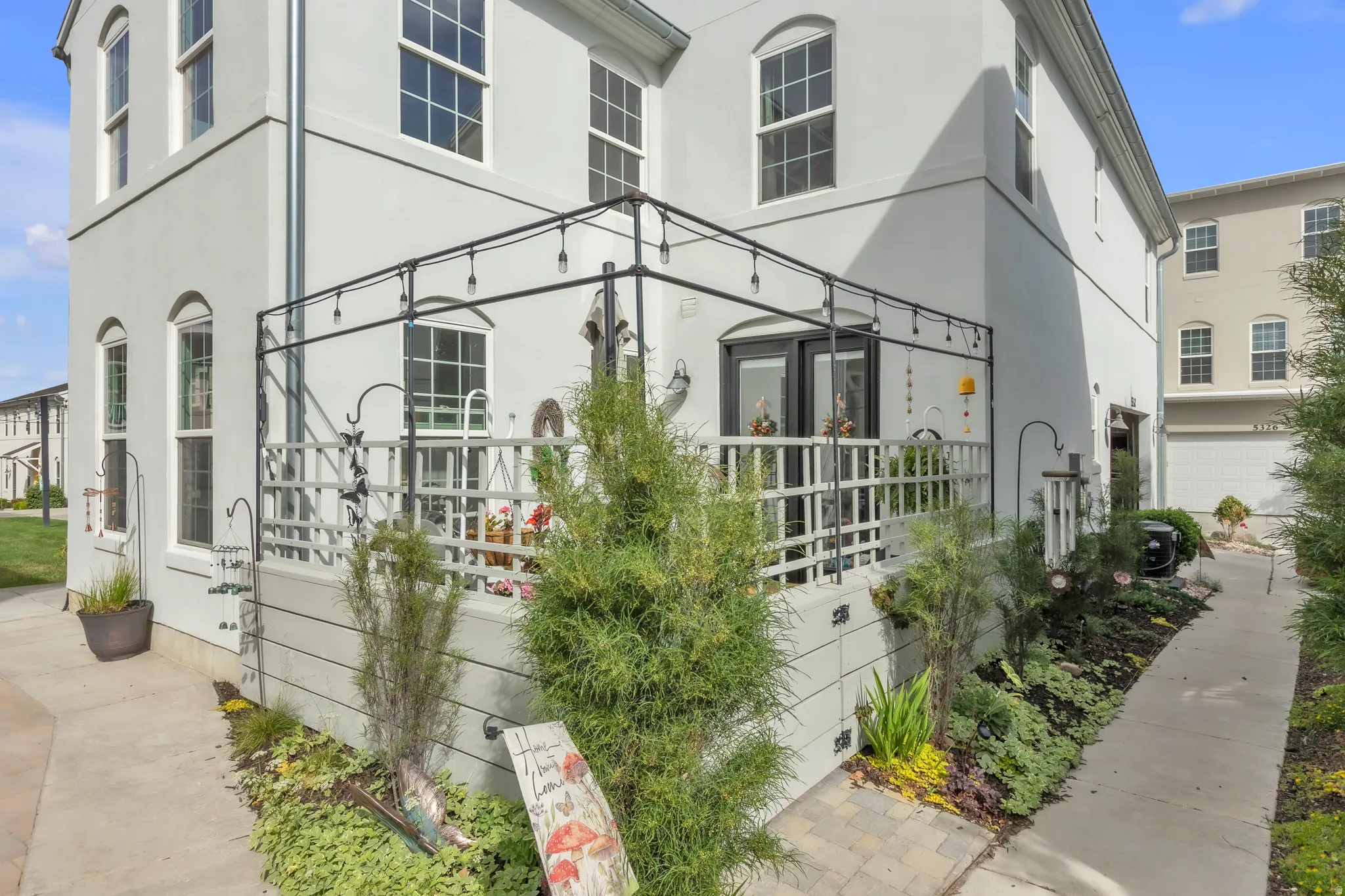 Exterior patio featuring a decorative metal overhead structure, white railing, and dual French doors