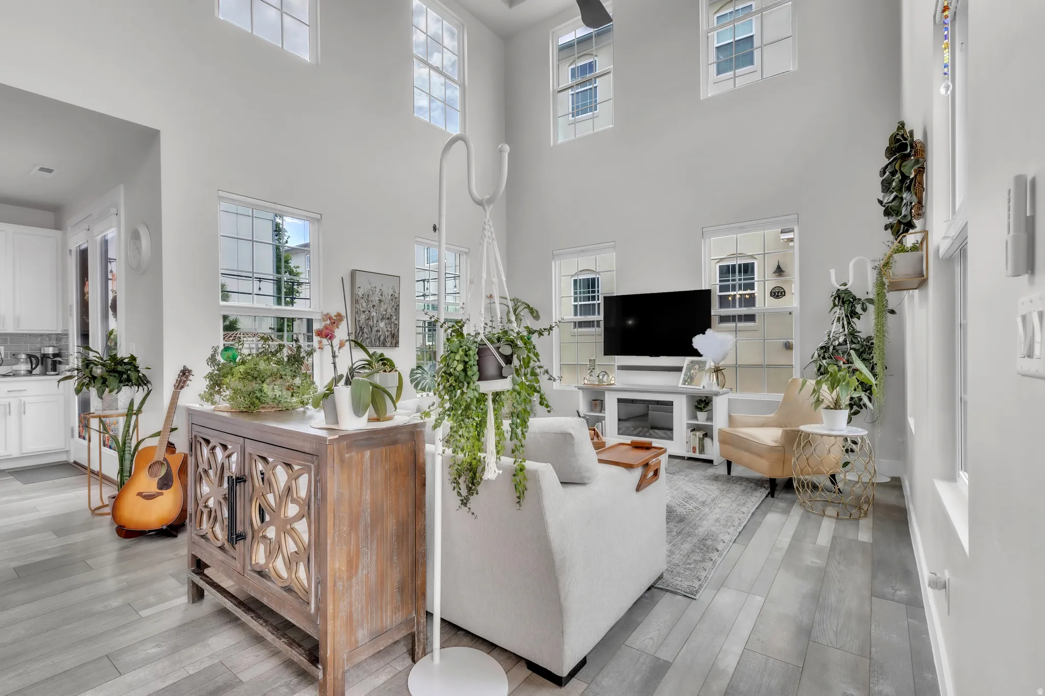 Living area featuring high ceilings, multiple transom windows, wood-finish flooring, and a ceiling fan