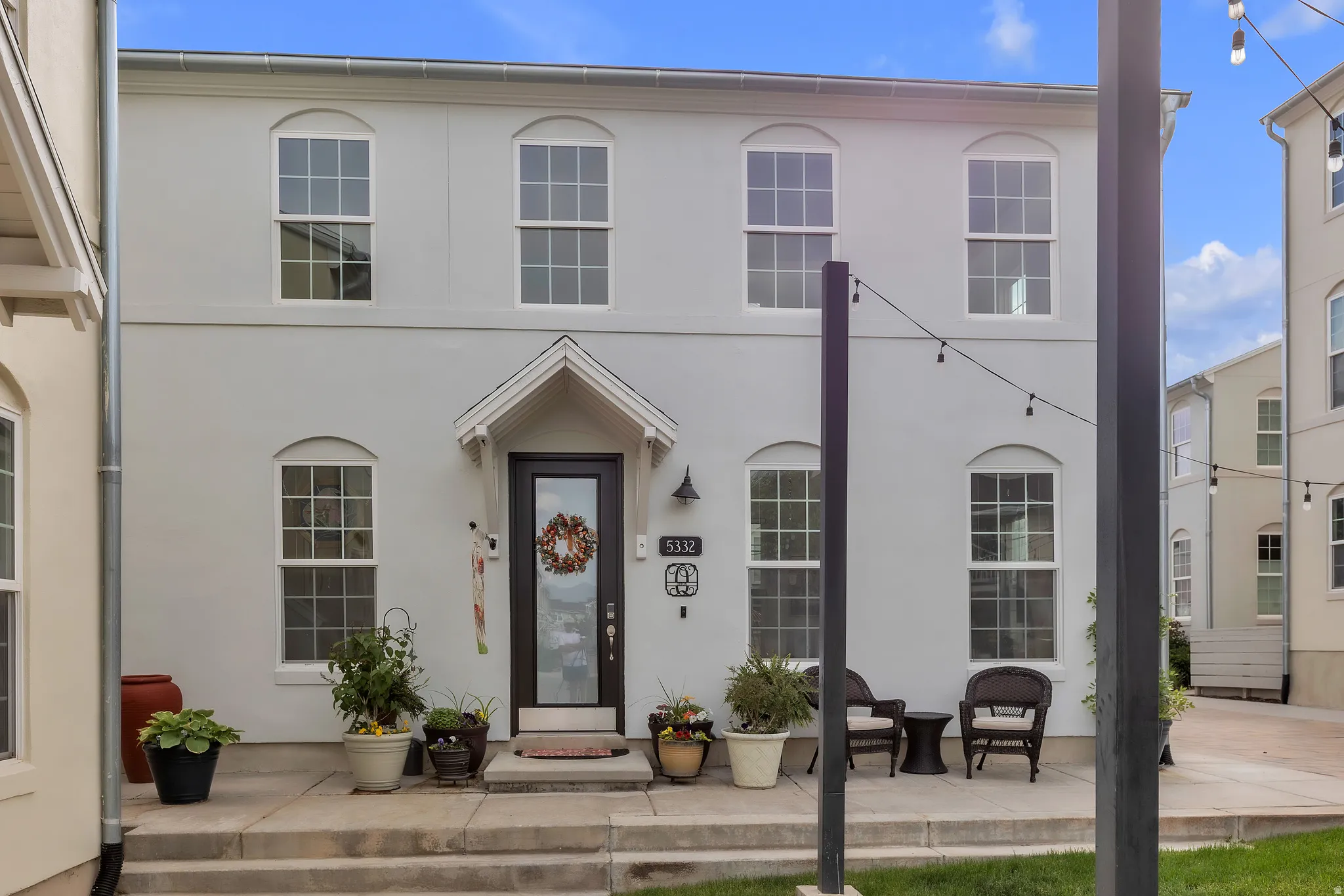 Two-story stucco exterior featuring a covered front porch and a dark-frame entry door with transom window