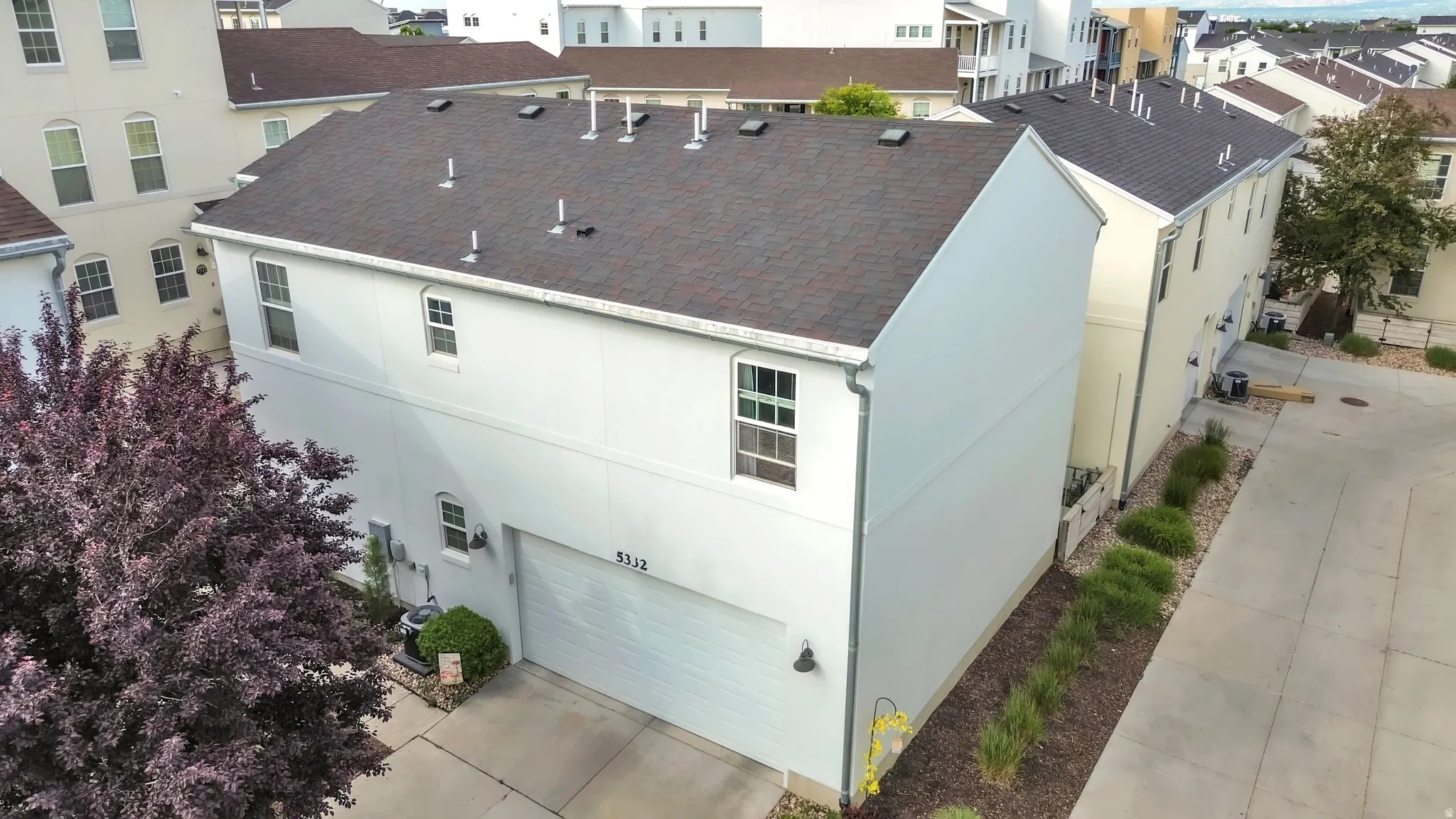 Two-story residence featuring a two-car garage with a white door, light-toned siding, and a dark shingle roof