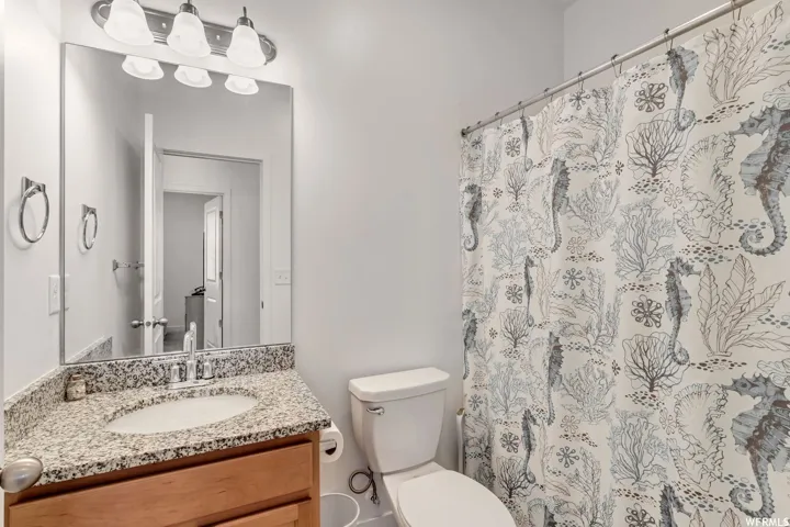Bathroom featuring a vanity with a granite countertop, undermount sink, and wood-finish cabinetry