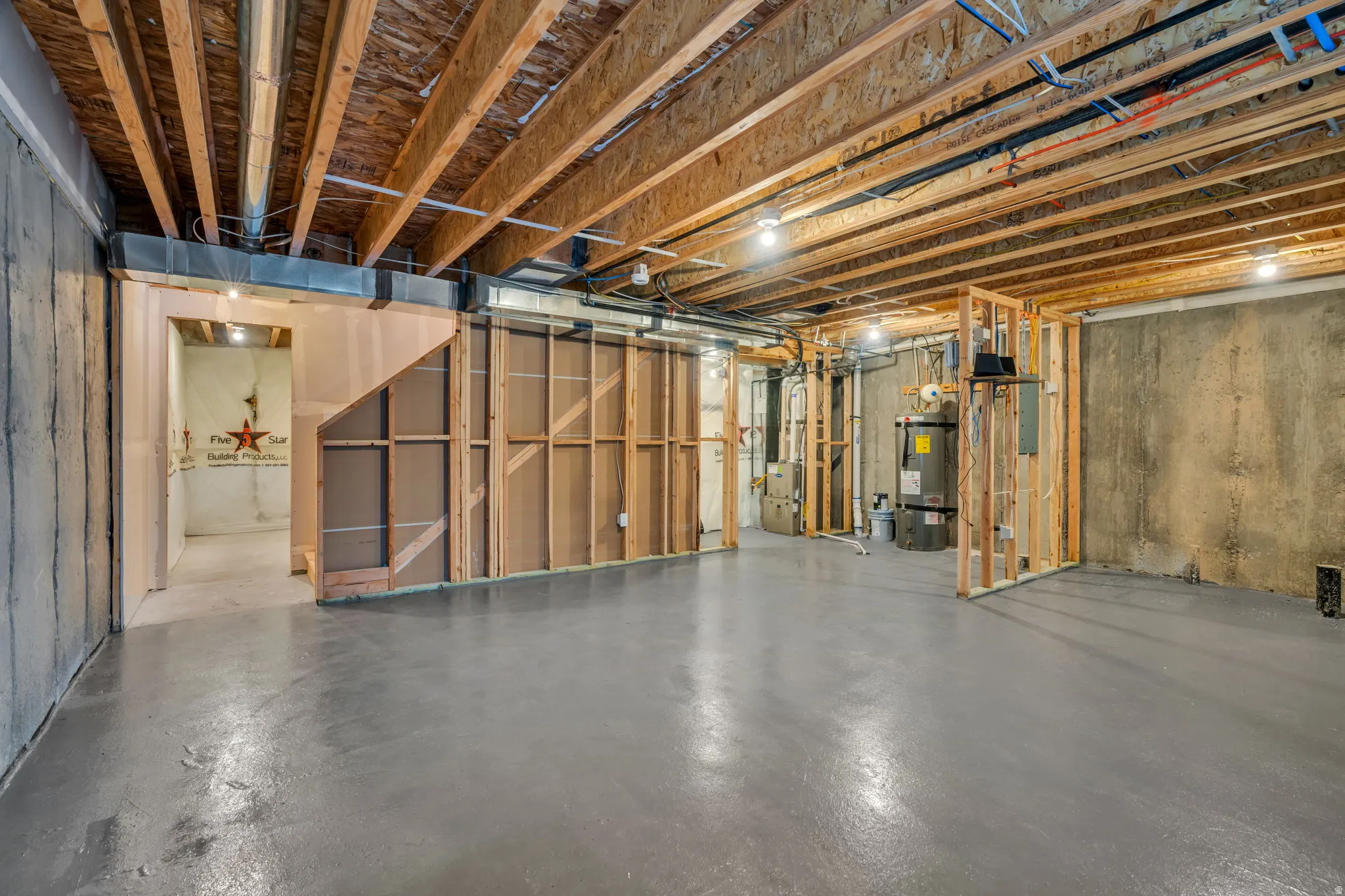 Expansive unfinished basement featuring exposed ceiling joists, concrete flooring, and partial wall framing