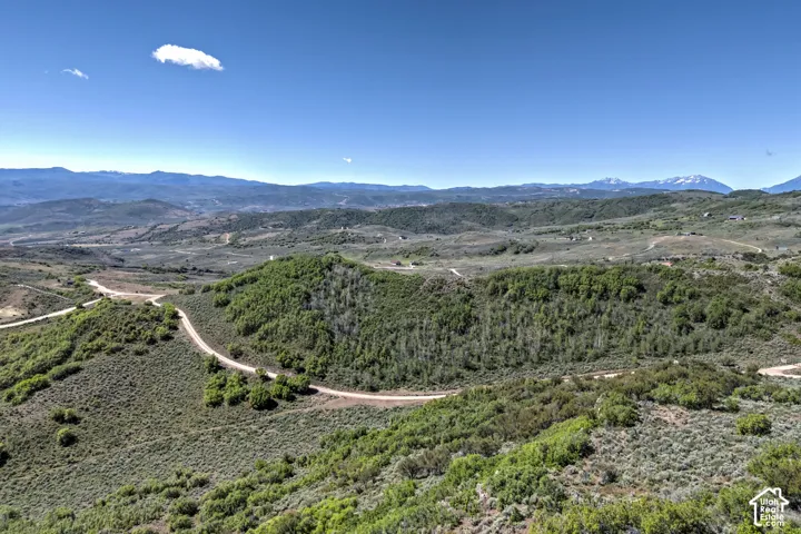 Expansive landscape with a clear sky, distant mountains, and winding unpaved roads