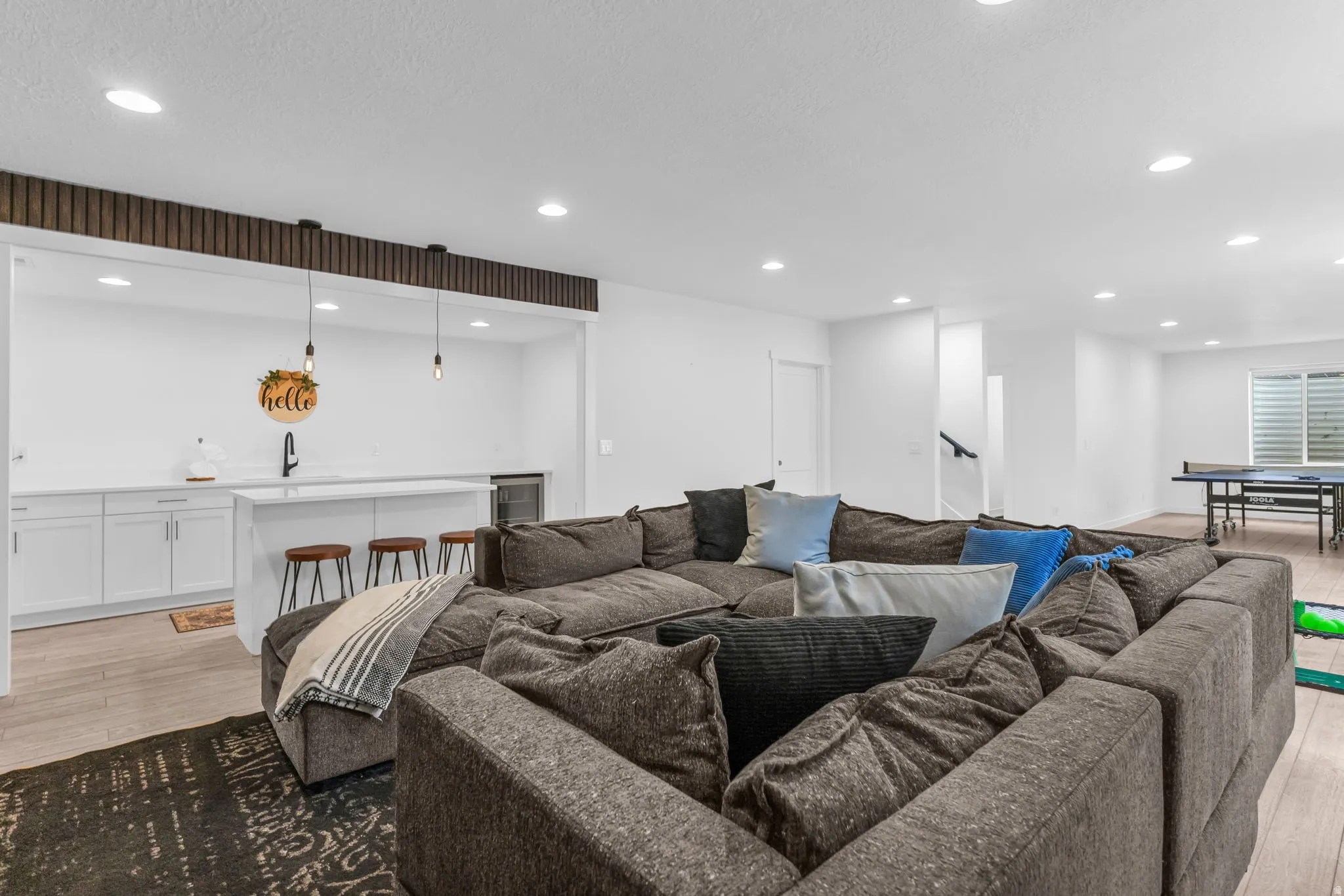 Spacious entertainment area featuring a built-in wet bar with white cabinetry, a quartz-look countertop, and a contemporary black faucet