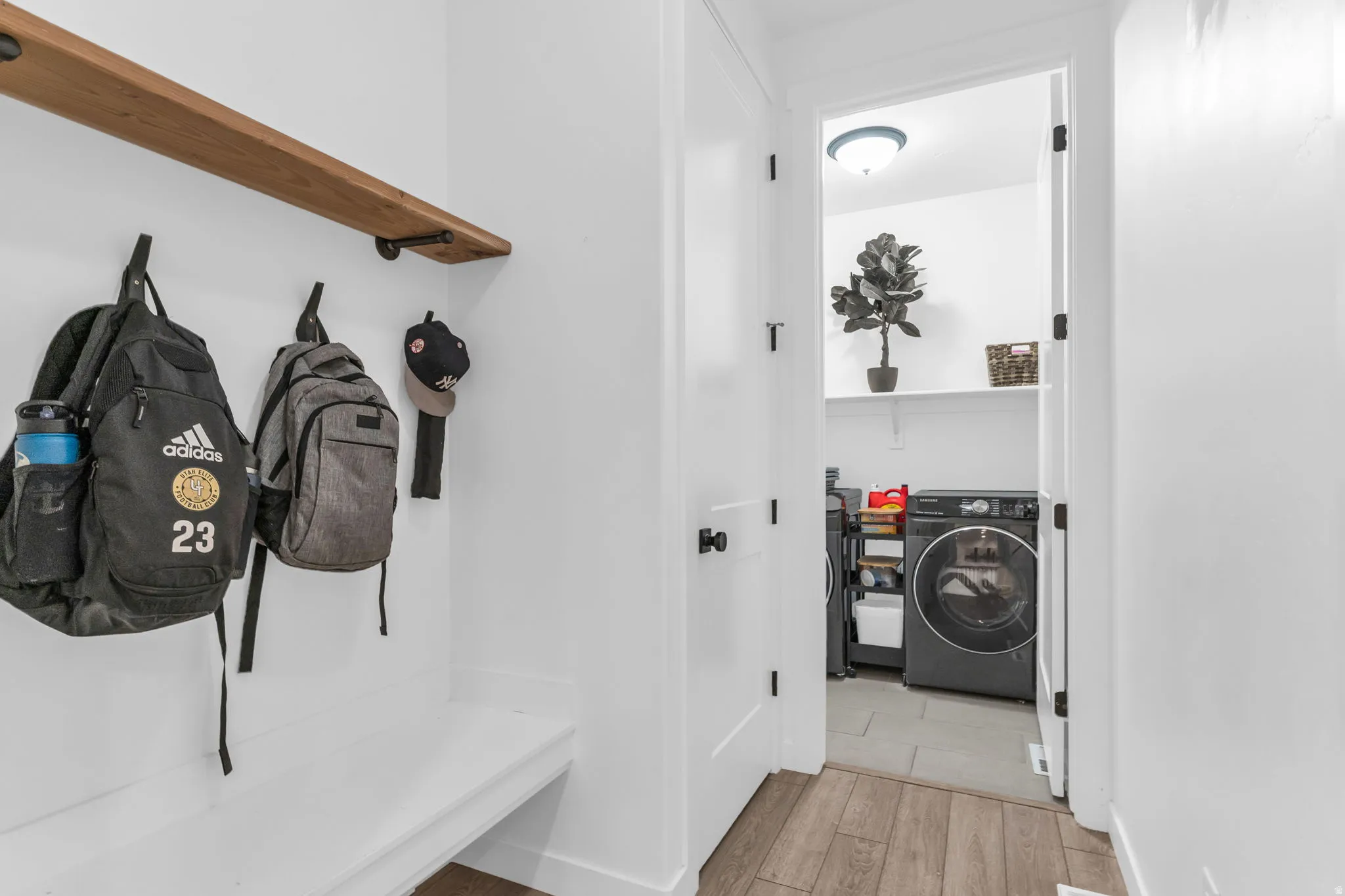 Mudroom area featuring a built-in bench, natural wood-finish floating shelf, and dark hardware